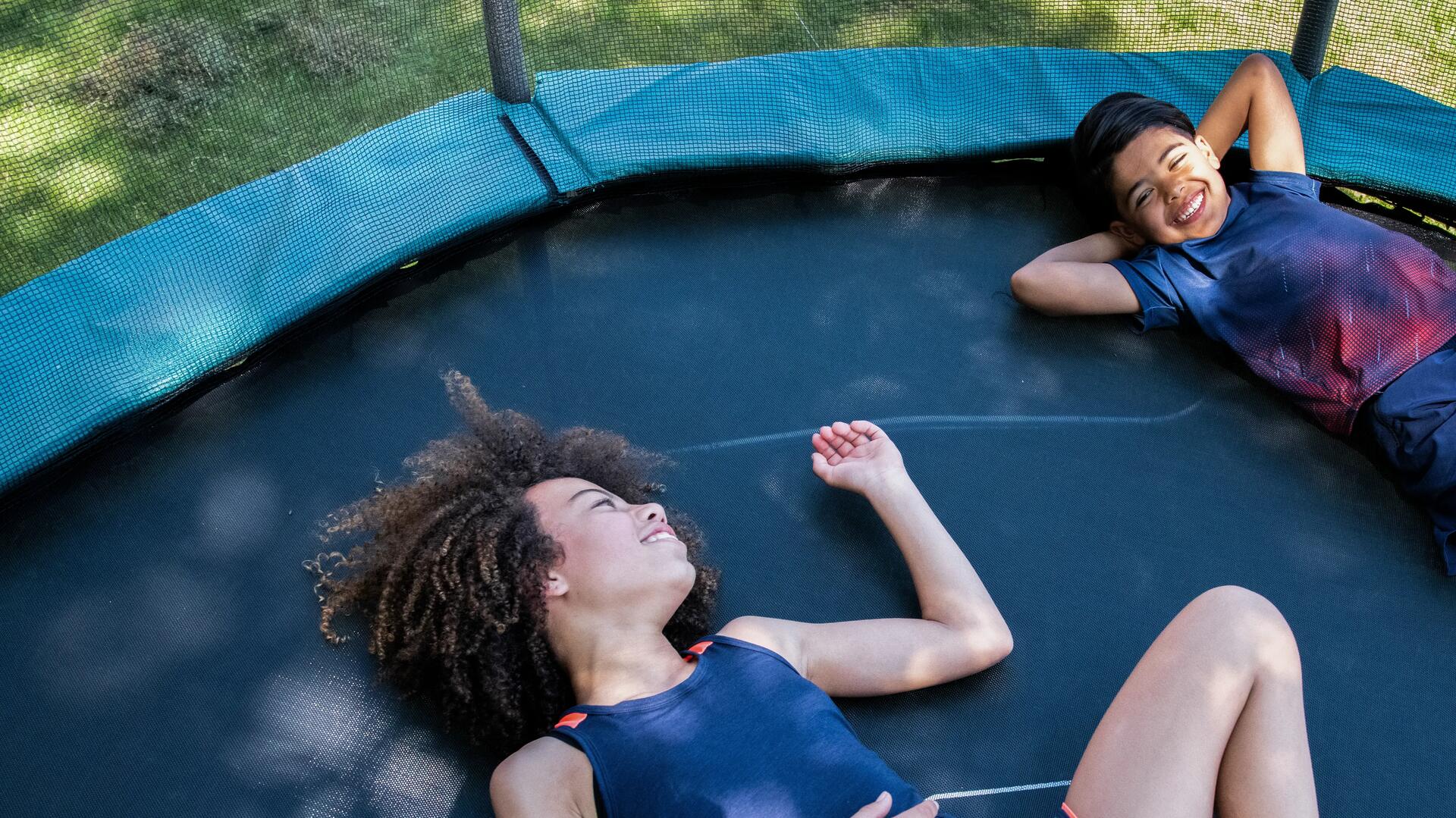 dzieci leżące na trampolinie w strojach sportowych