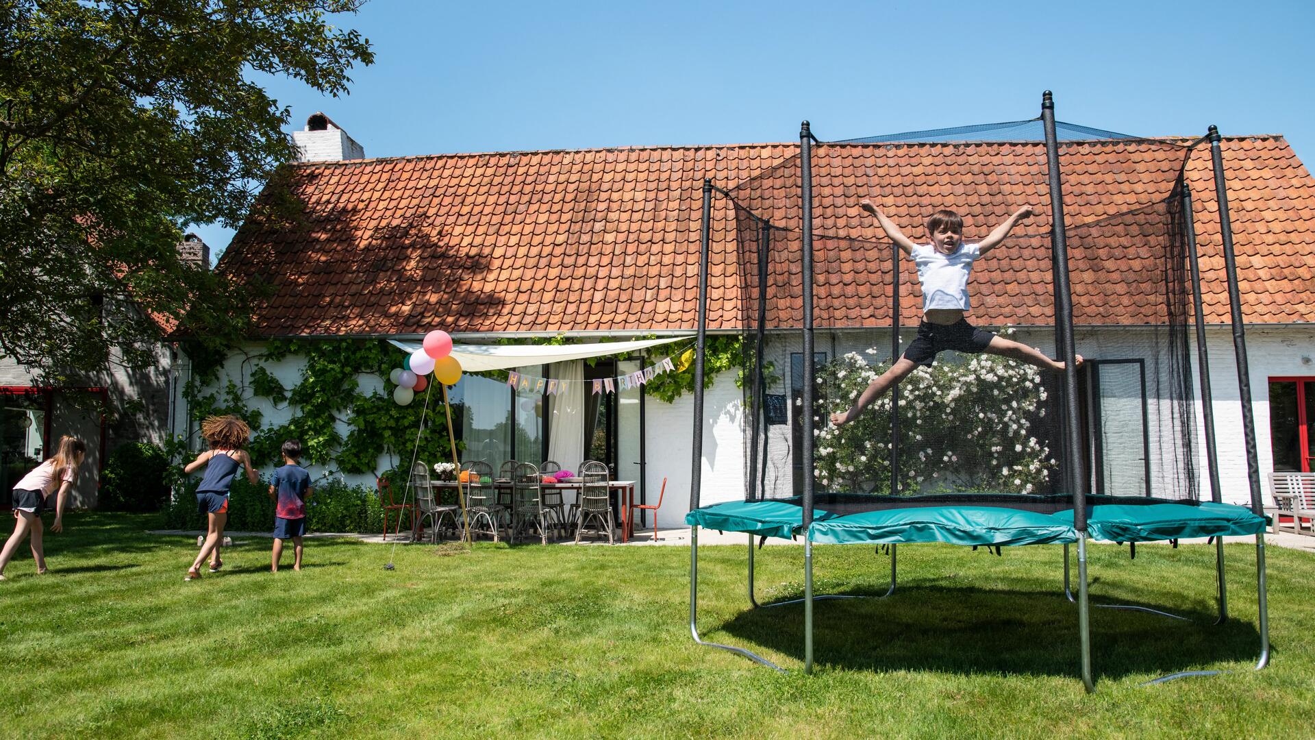 dziecko skaczące na trampolinie ogrodowej z siatką