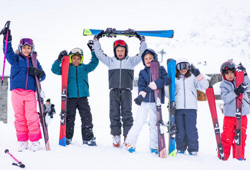 Barn som står med skidor i snön