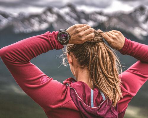 kobieta zawiązująca włosy ze smartwatchem na ręce w górach