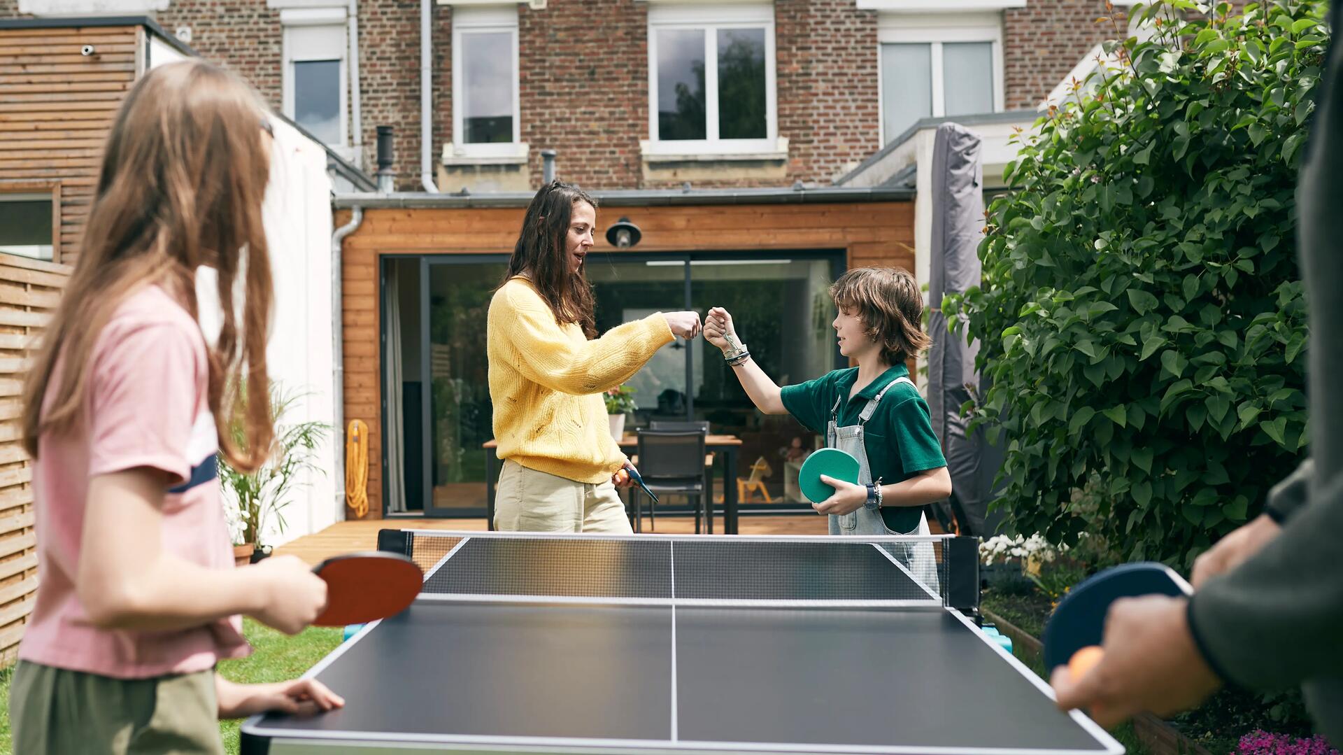 familia a jogar ping pong no exterior de casa