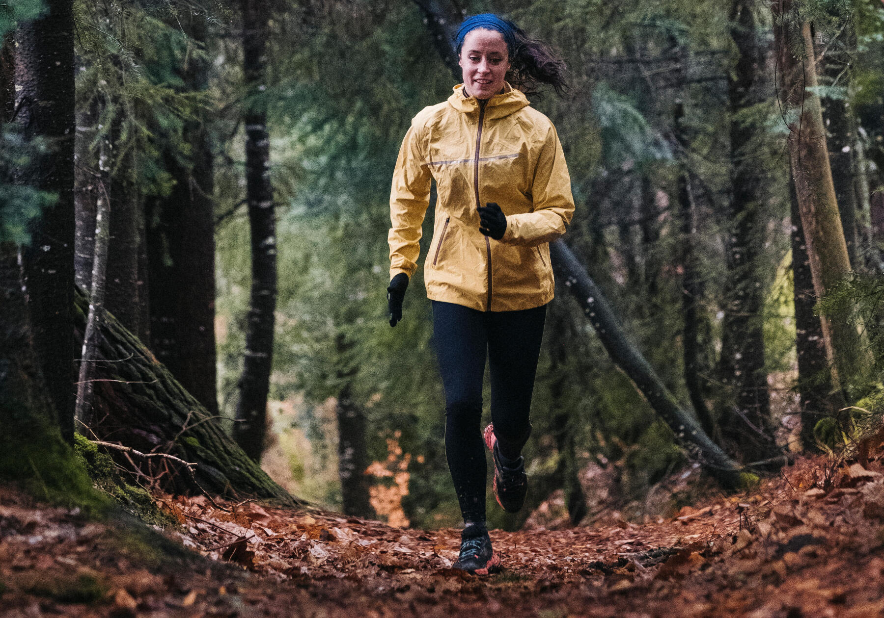 woman watching the terrain while running on a trail in the fall