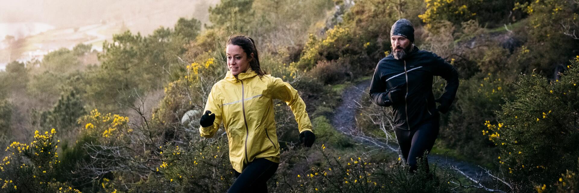 mężczyzna i kobieta w odzieży do biegania w terenie biegnący po trasie z naturalnymi przeszkodami