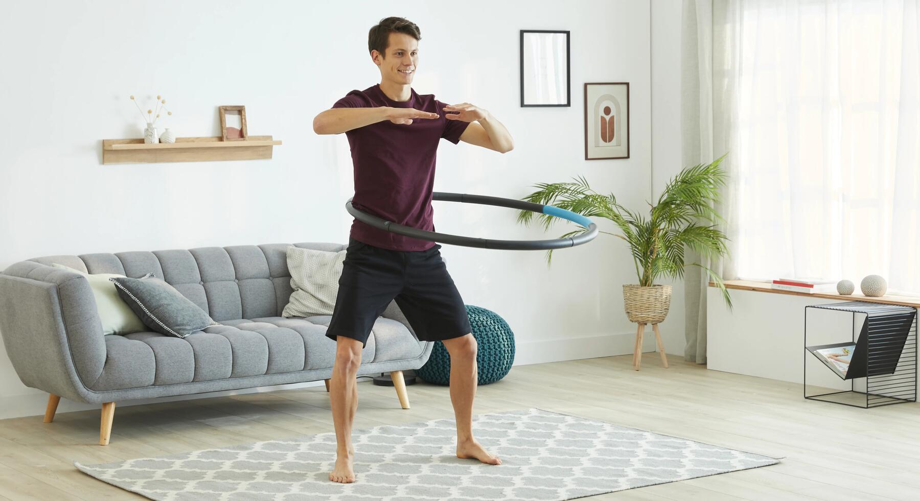 A man using a weighted hoop in his living room