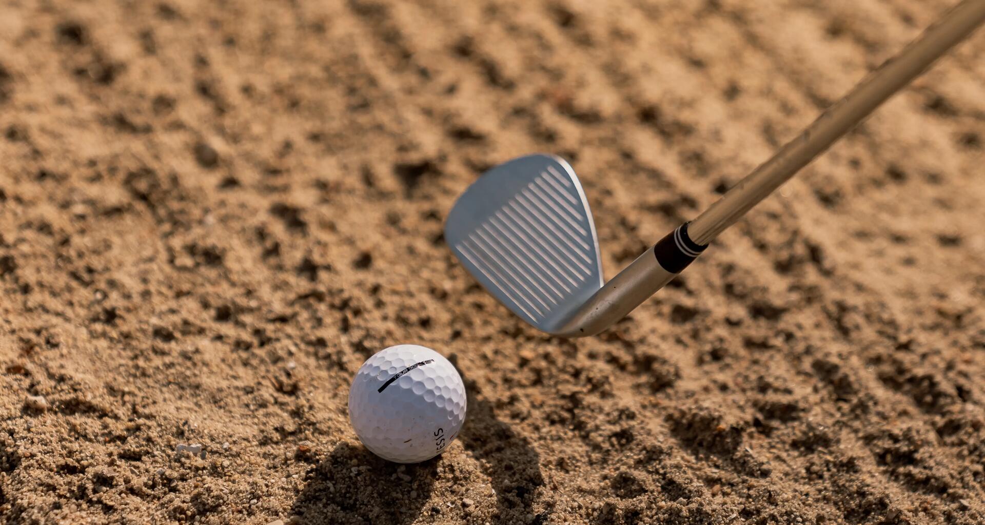 kij golfowy z piłeczką do golfa leżącą na ziemi