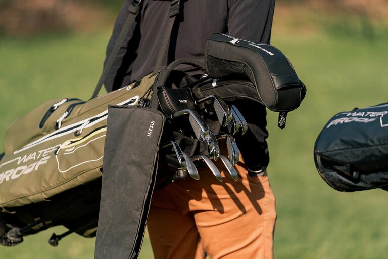 Golf towel attached to a golf bag beside a set of golf clubs