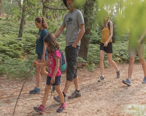 dois adultos e uma criança a caminhar na floresta decathlon