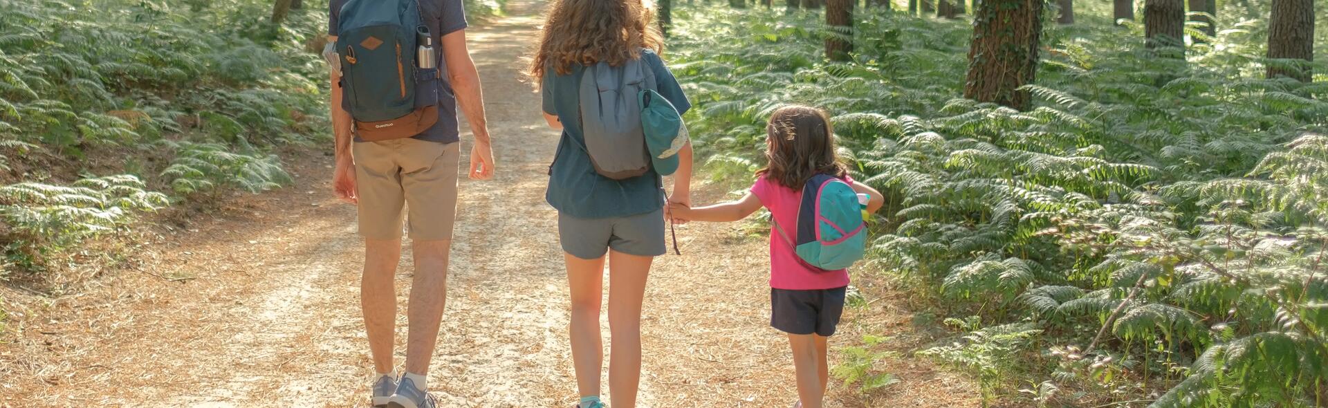 dois adultos e uma criança a caminhar na floresta decathlon