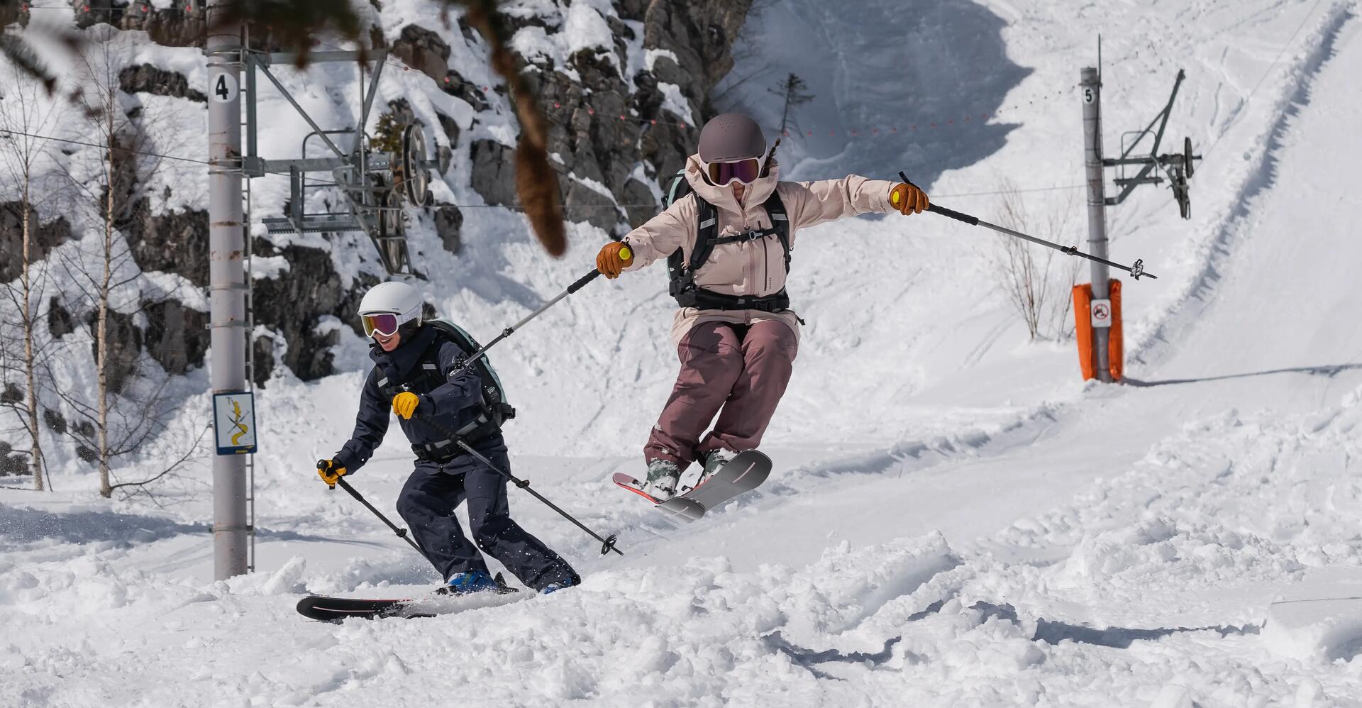 kobieta i mężczyzna w odzieży i kaskach narciarskich zjeżdżający ze stoku na nartach