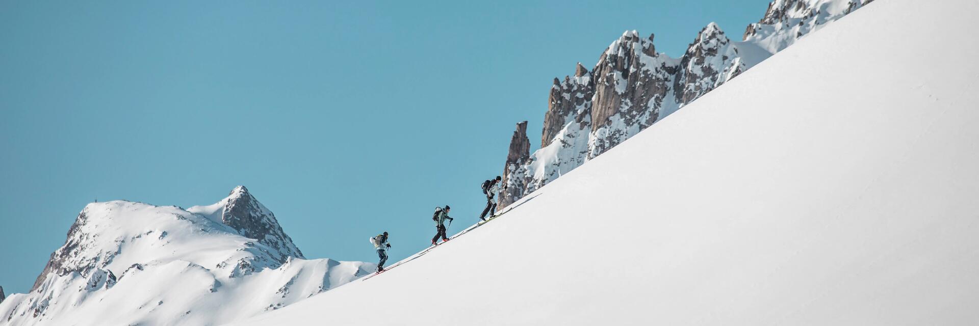 Skialpinisti šliapajúc hore zasneženým kopcom