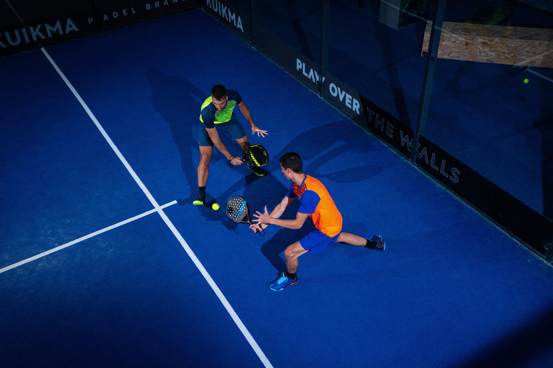 Twee mannen die aan het padellen zijn, en een van de twee mannen slaat een padel volley.