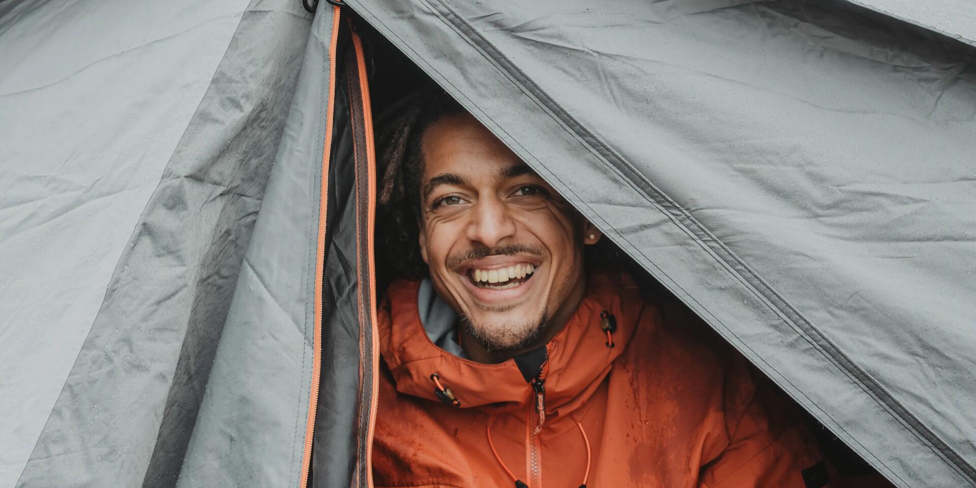 mężczyzna siedzący w namiocie w kurtce trekkingowej