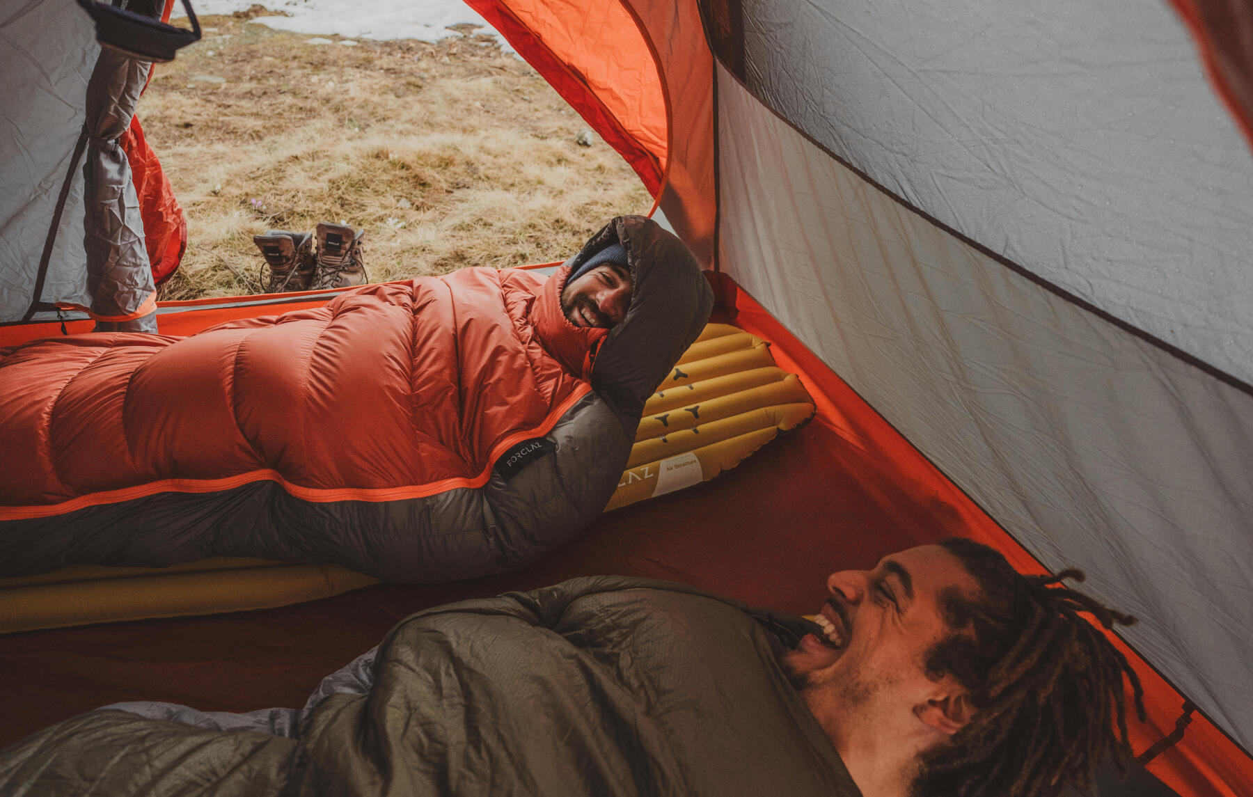 two men in their sleeping bags, inside their tent