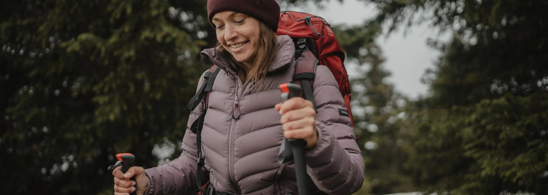 Woman hiking with nordic walking poles, wearing down jacket