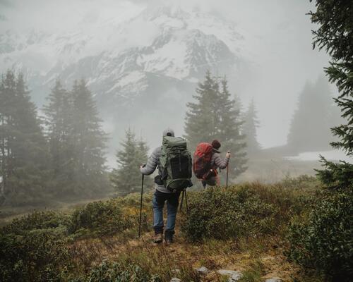 Kobieta i mężczyzna z plecakami trekkingowymi na plecach wędrujący po górach w deszczowy dzień 