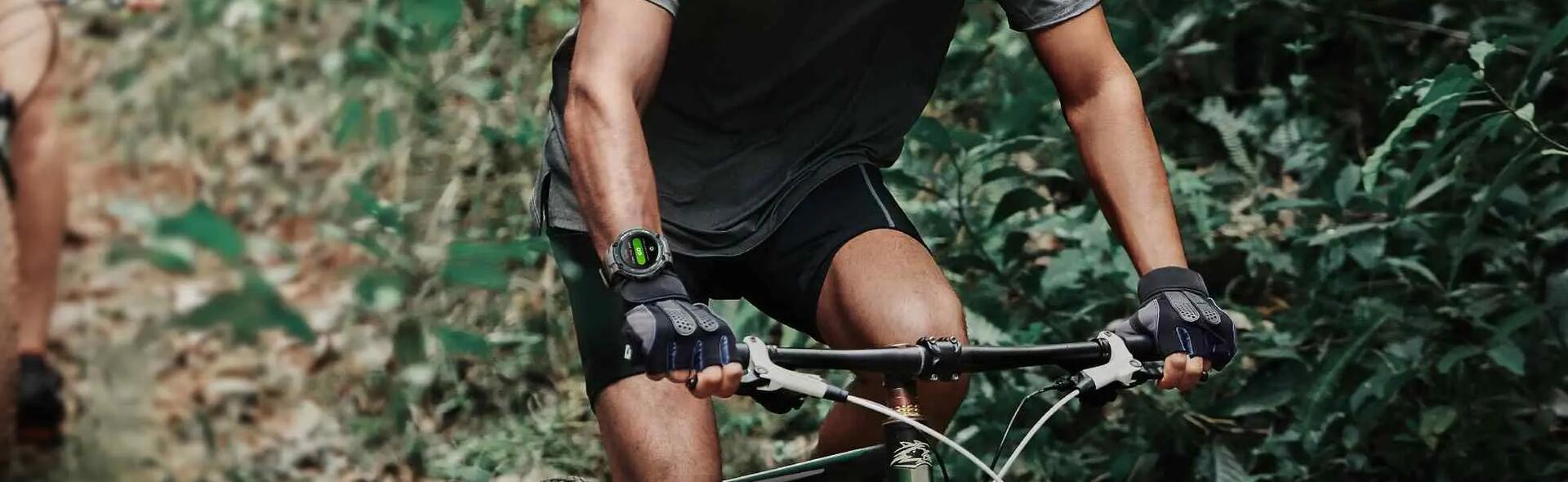 mężczyzna jadący na rowerze w kasku ze smartwatchem na ręce