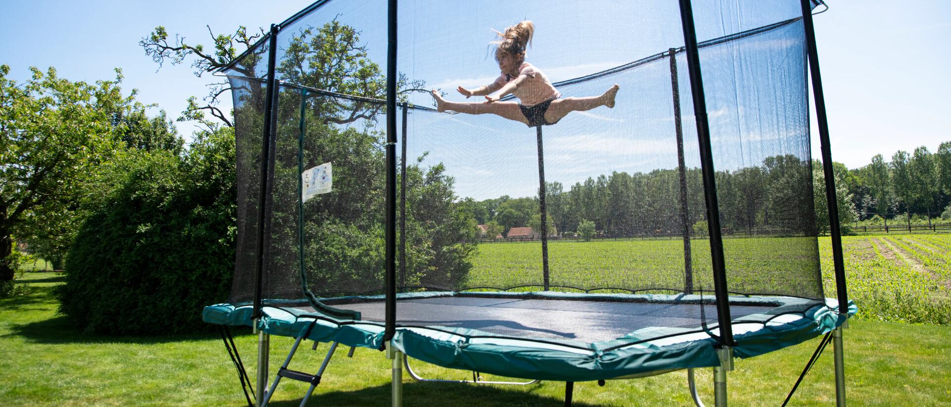 Young girl jumping on outdoor trampoline, doing splits in the air