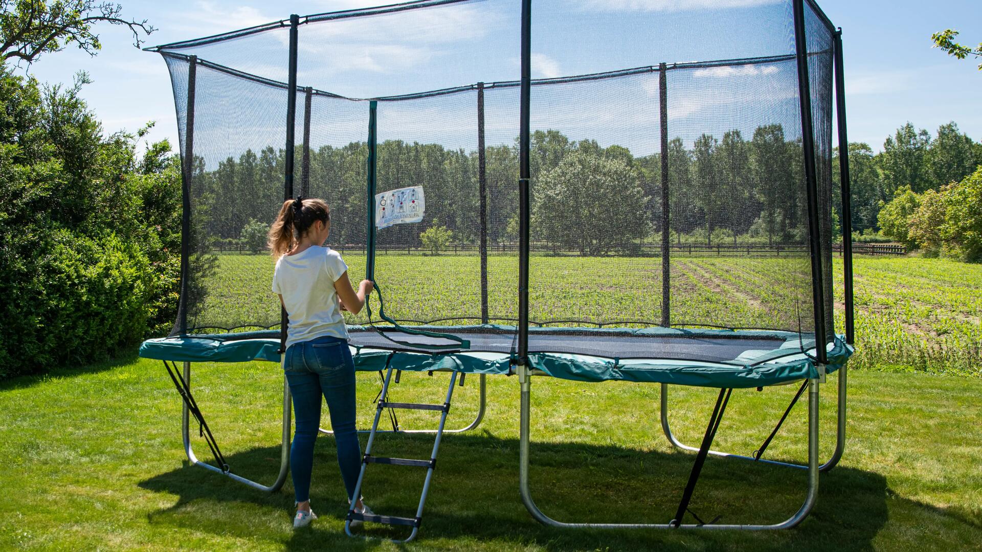 kobieta odpinająca siatkę od trampoliny ogrodowej