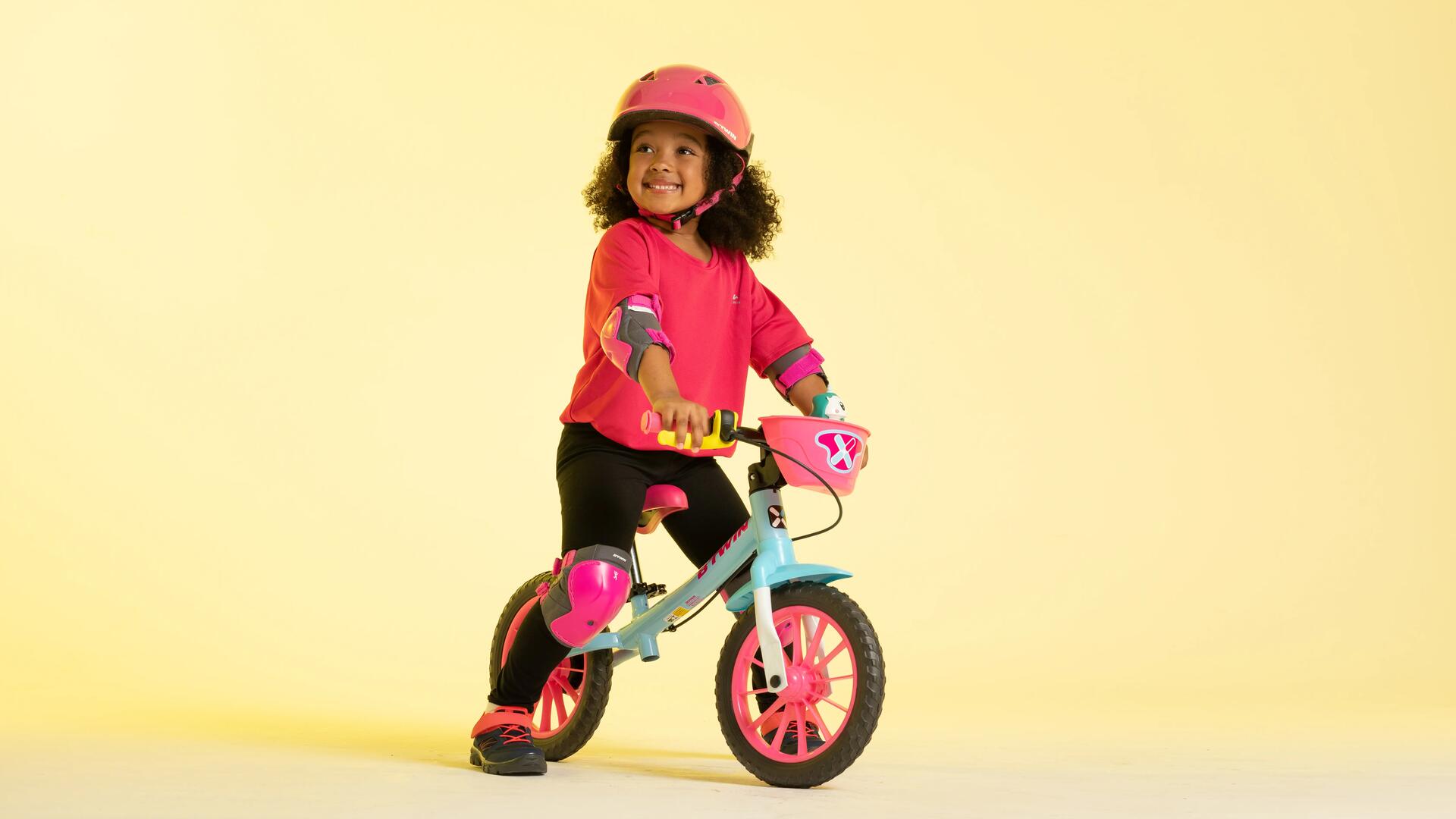dziewczynka w kasku rowerowym siedząca na rowerze biegowym 