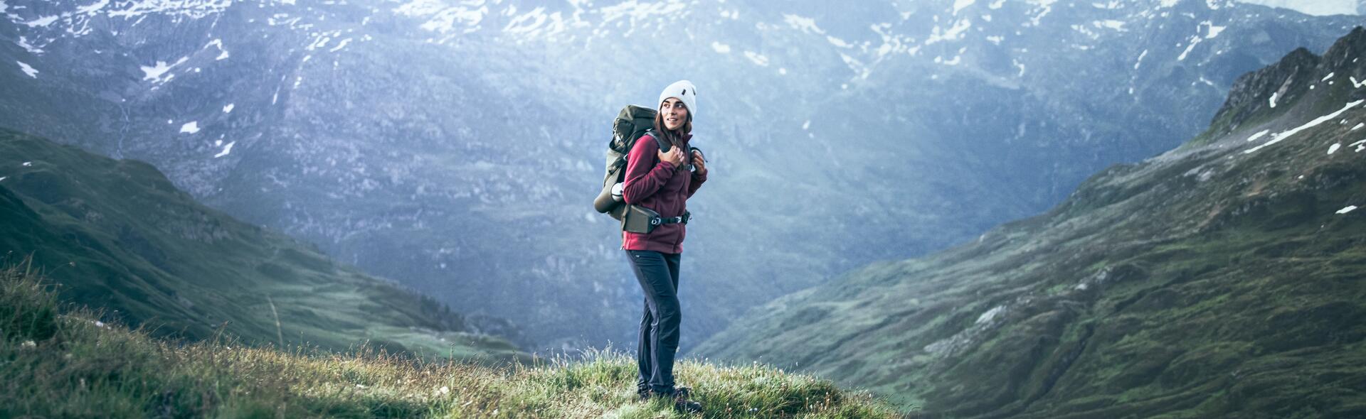 kobieta w odzieży trekkingowej z plecakiem na plecach stojąca w górach