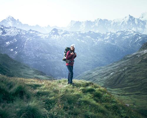 kobieta w odzieży trekkingowej z plecakiem na plecach stojąca w górach