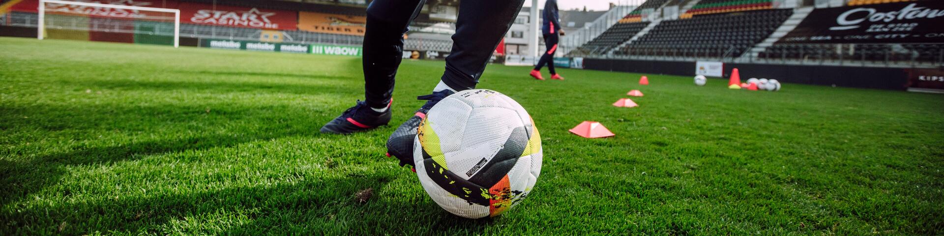 A man doing training drills with a football inside a stadium