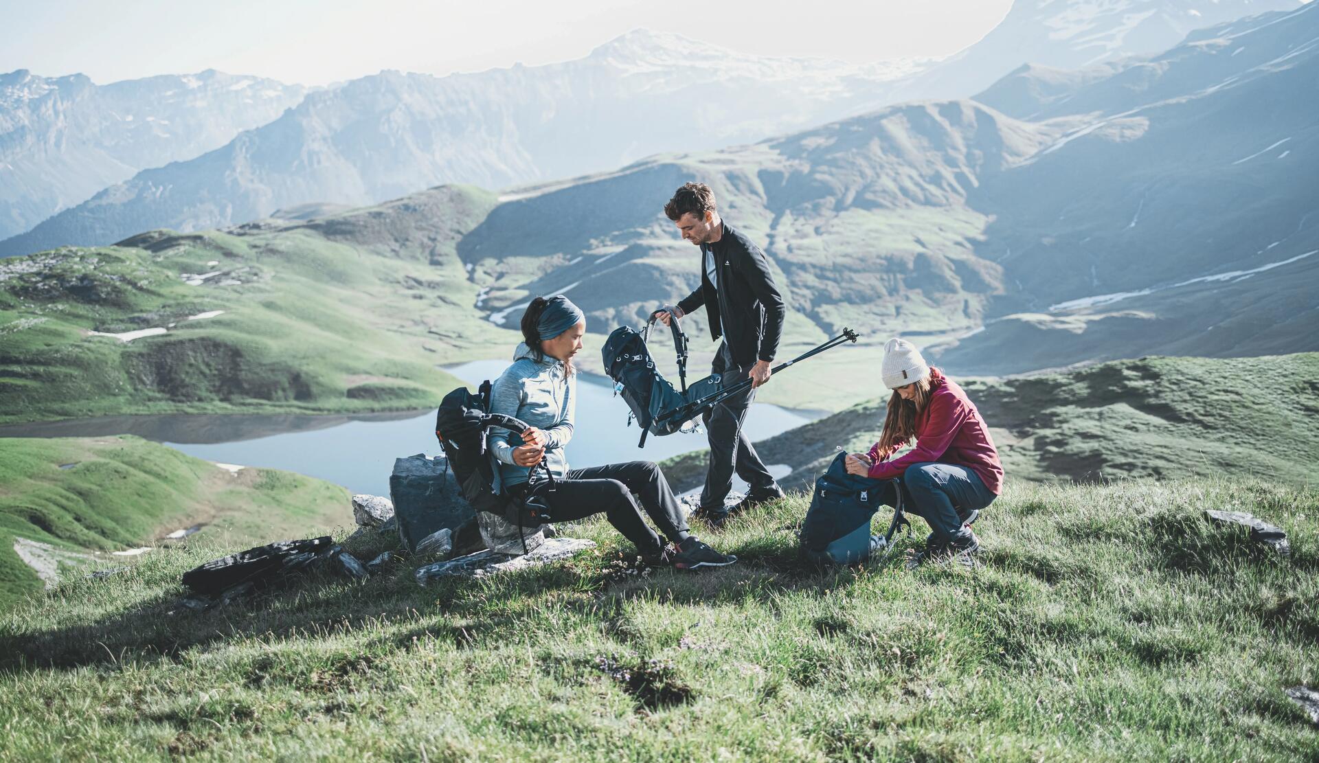 kobiety i mężczyzna w odzieży trekkingowej odpoczywający w górach