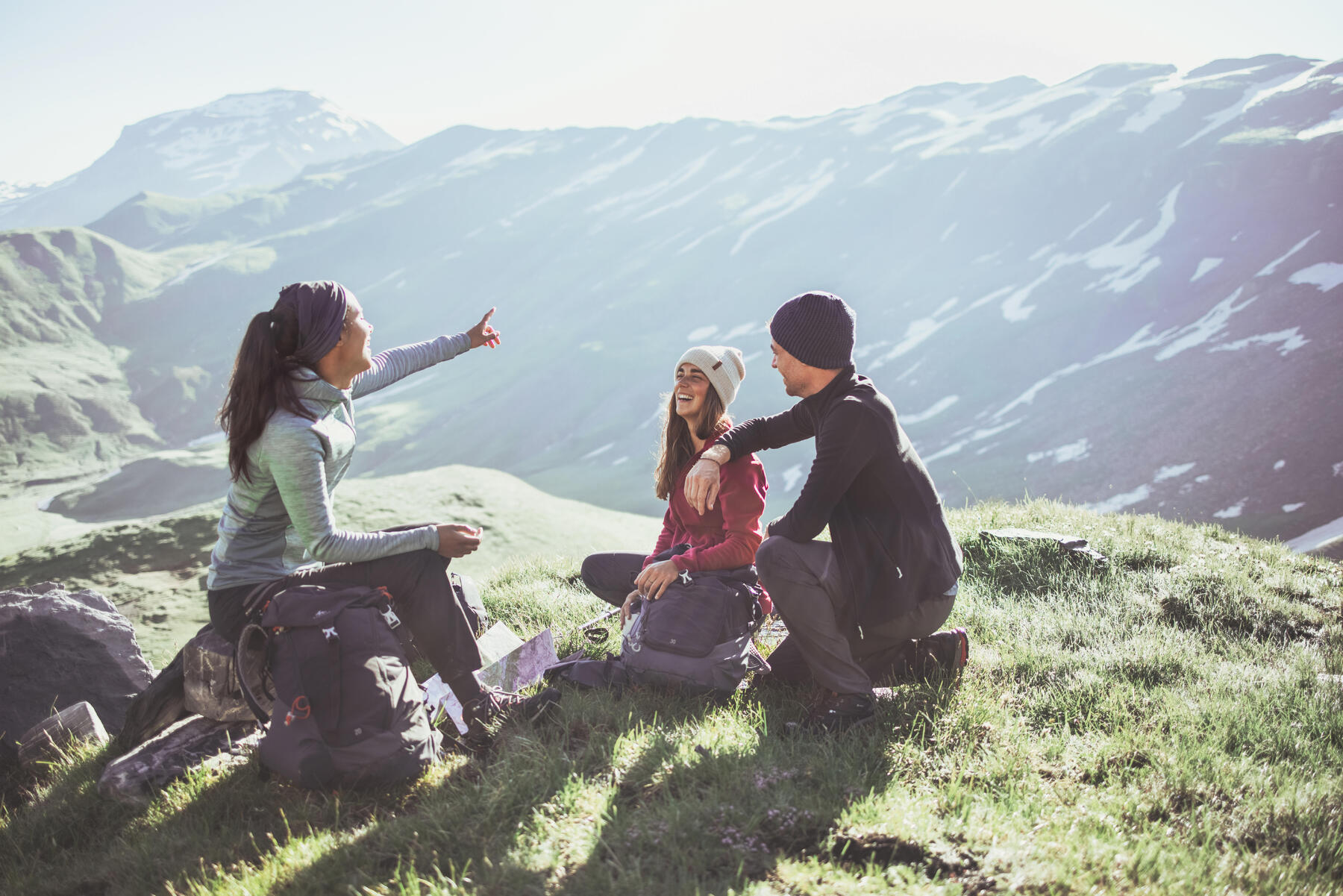 Eine Gruppe aus 3 Personen sitzt auf einen Berg und zeigt in die Höhe. Sie haben durch Akrophobie ihre Höhenangst überwunden
