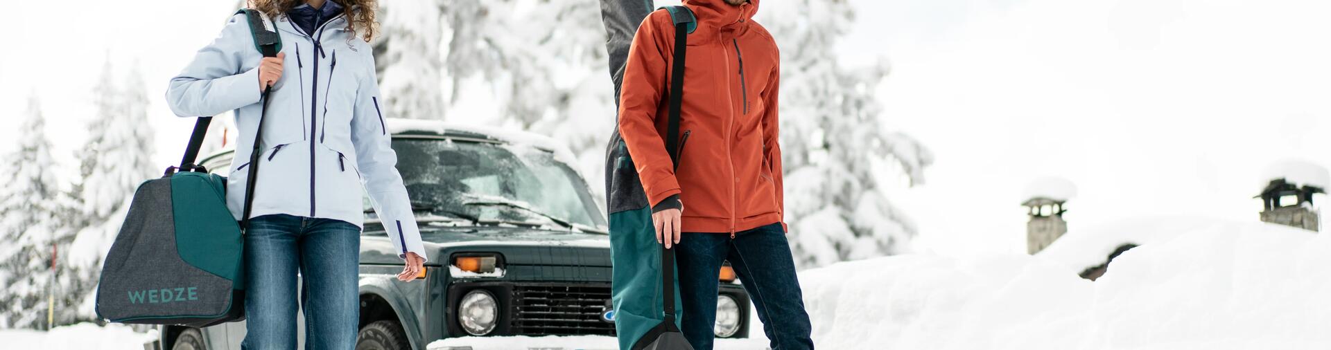 Man and woman carrying their ski equipment