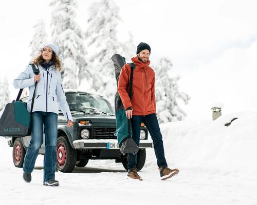 Man and woman carrying their ski equipment