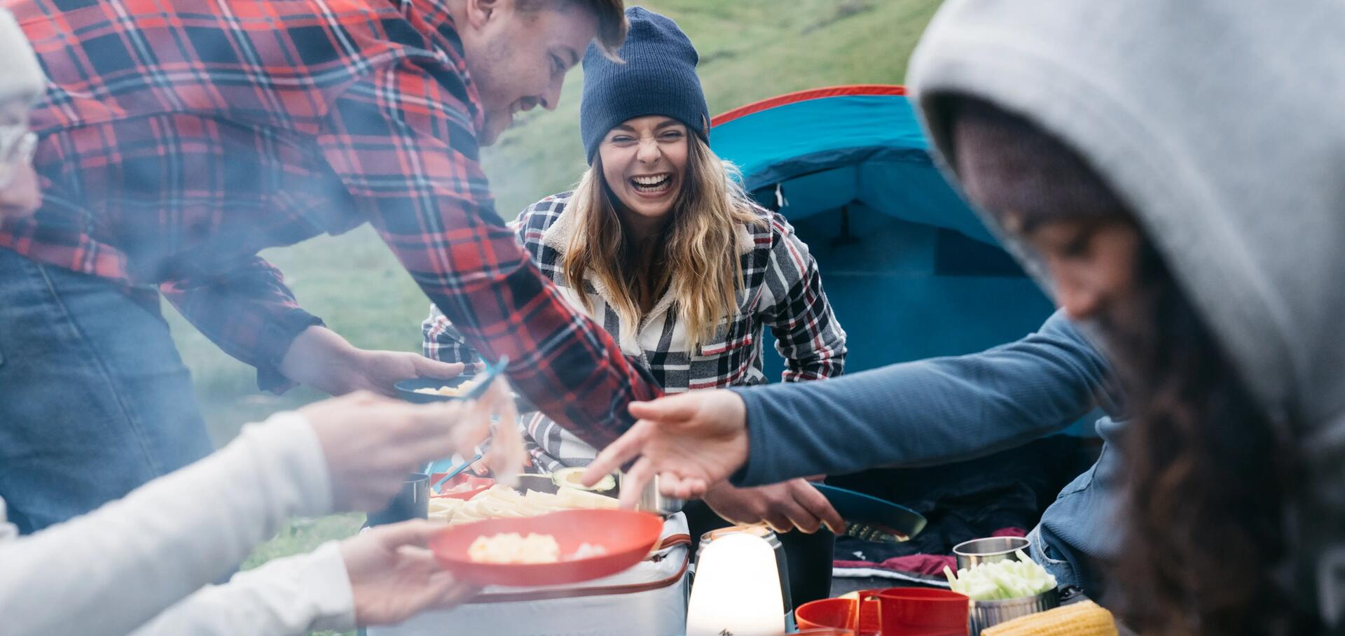 kobiety i mężczyźni spędzający czas przed namiotem jedząc wspólny posiłek