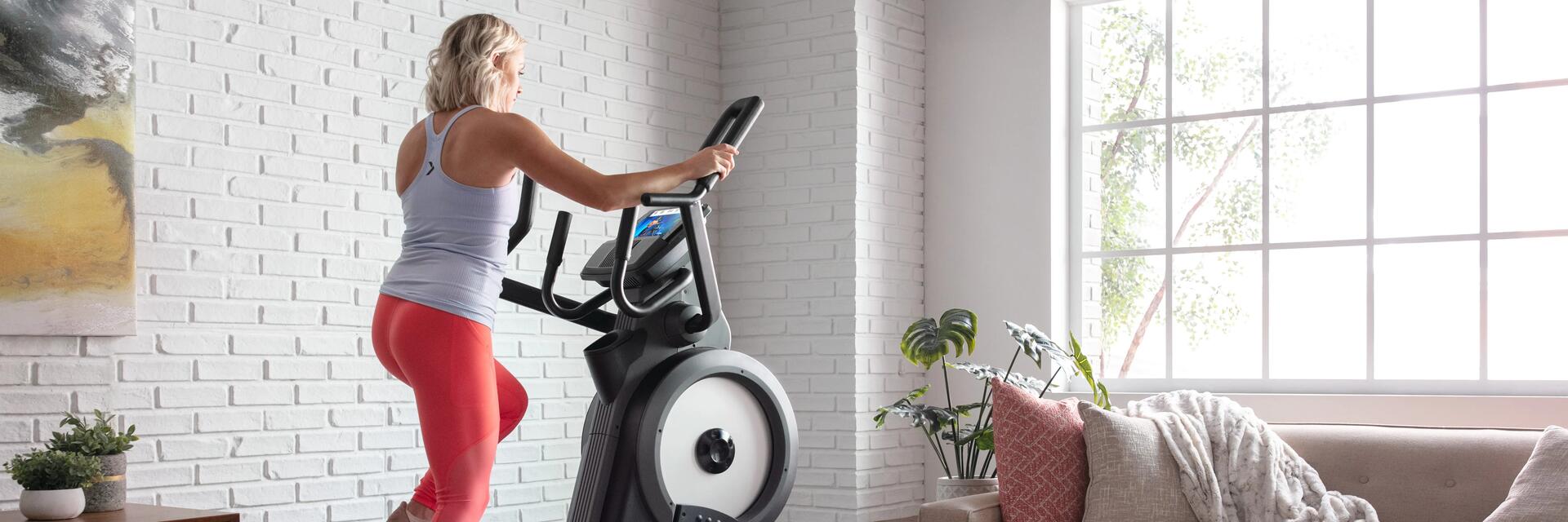 Een vrouw in haar woonkamer op een crosstrainer