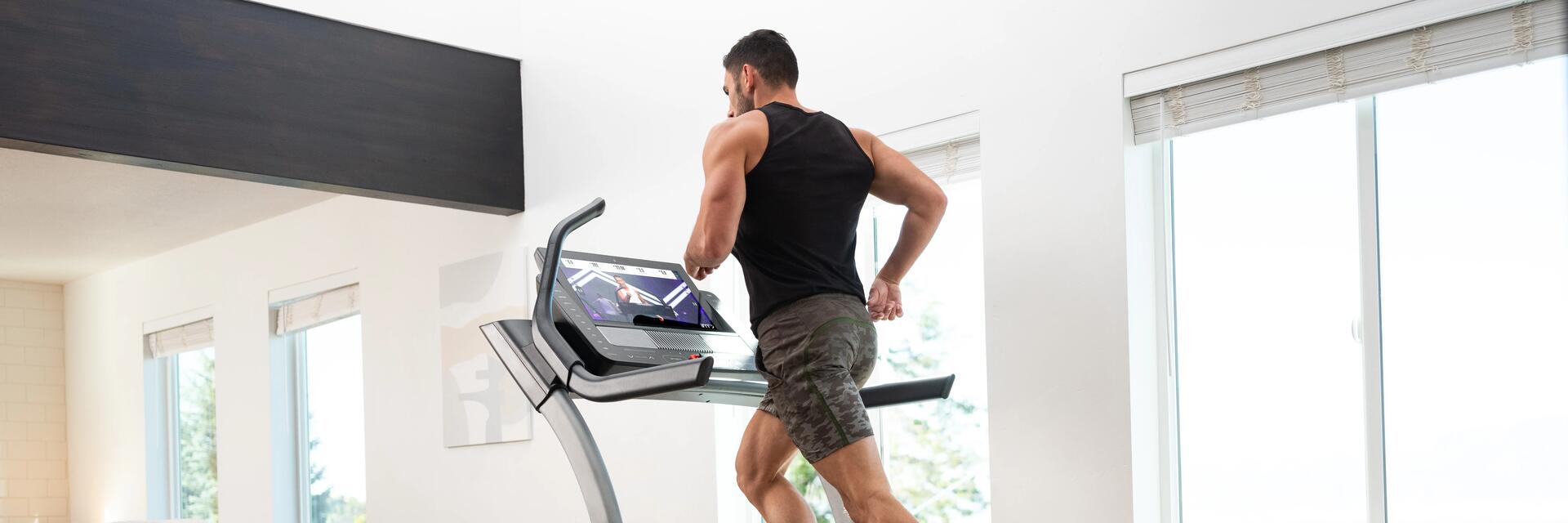 Ein Mann steht in Kleidung für Cardiotraining auf dem Laufband