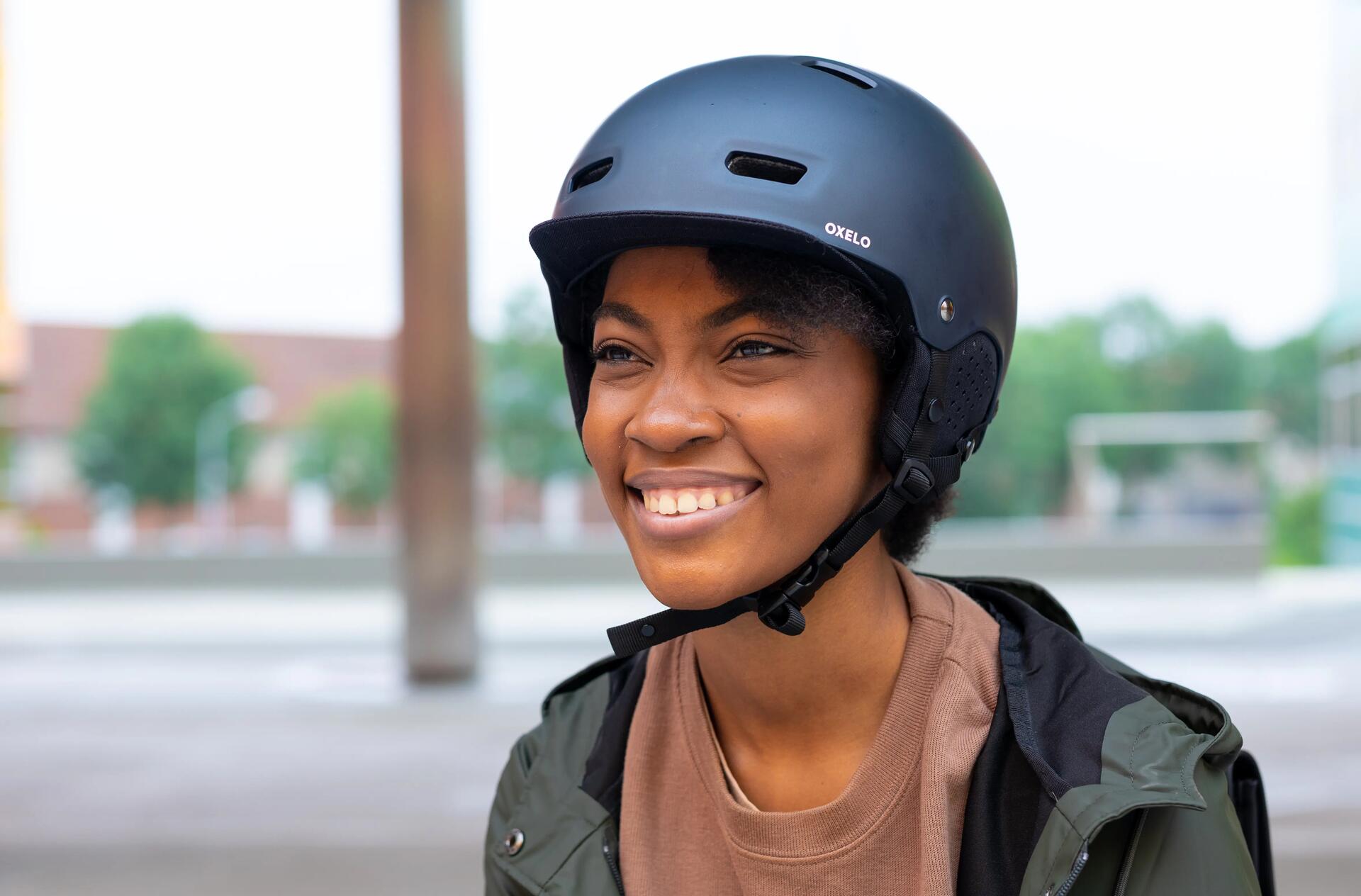 uśmiechnięta kobieta w czarnym kasku do jazdy na hulajnodze