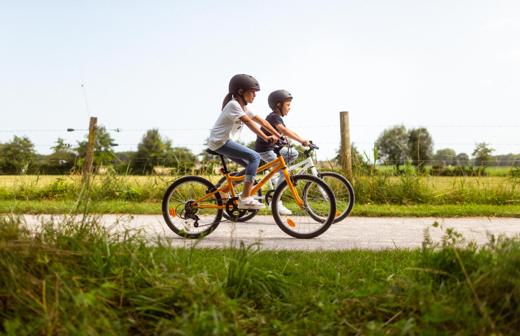 Två barn cyklar längst en landsväg