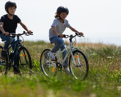Duas crianças a andar de bicicleta na natureza