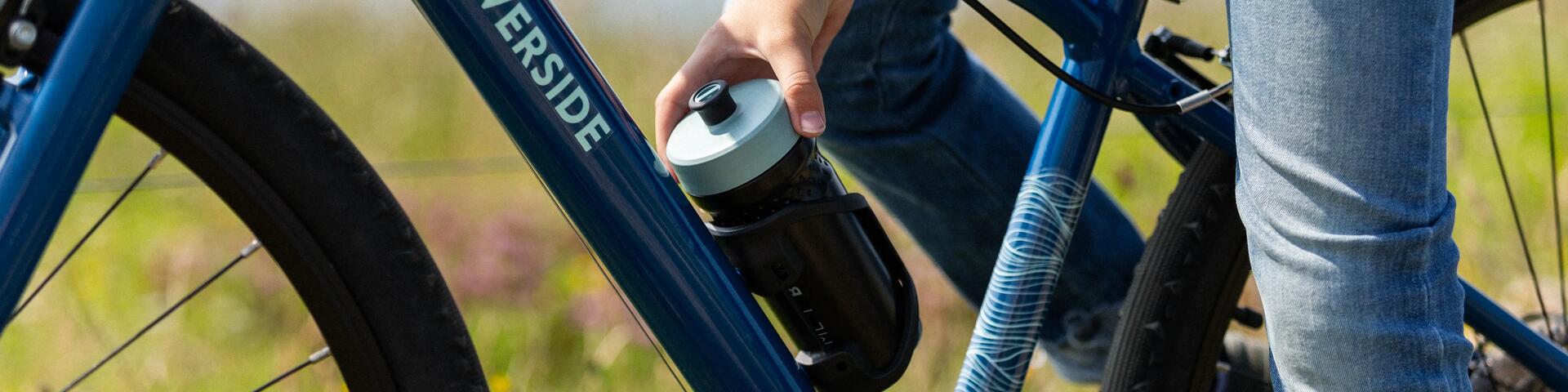 A cyclist grabbing their water bottle from the bottle cage on a Riverside hybrid bike