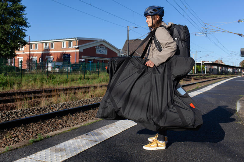 Kobieta transportuje rower pociągiem w specjalnym pokrowcu