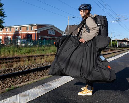 Kobieta transportuje rower pociągiem w specjalnym pokrowcu