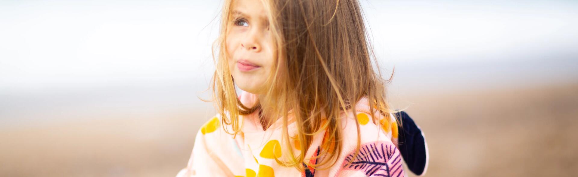 Menina com poncho Nabaiji rosa na praia