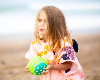 Menina com poncho Nabaiji rosa na praia