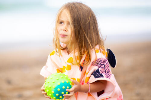 Menina com poncho Nabaiji rosa na praia