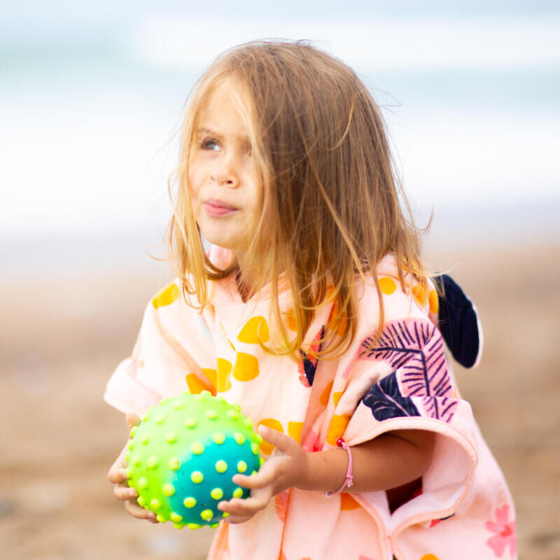 Menina com poncho Nabaiji rosa na praia