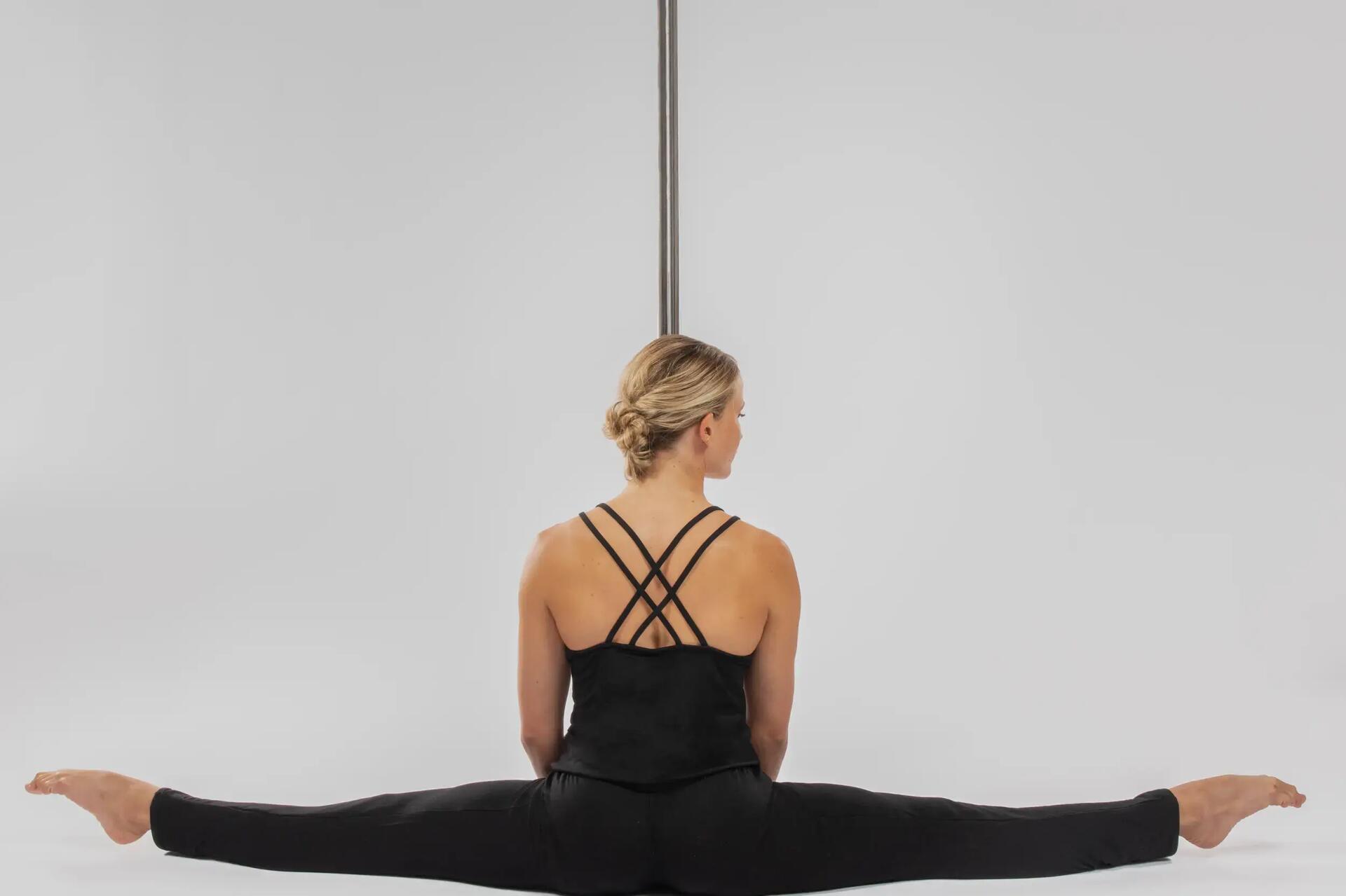 Kobieta rozciągająca się przed treningiem przy zamontowanej rurze do pole dance