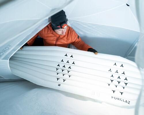 Man putting a sleeping pad on a tent at night 