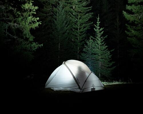 Namiot turystyczny rozbity w lesie nocą