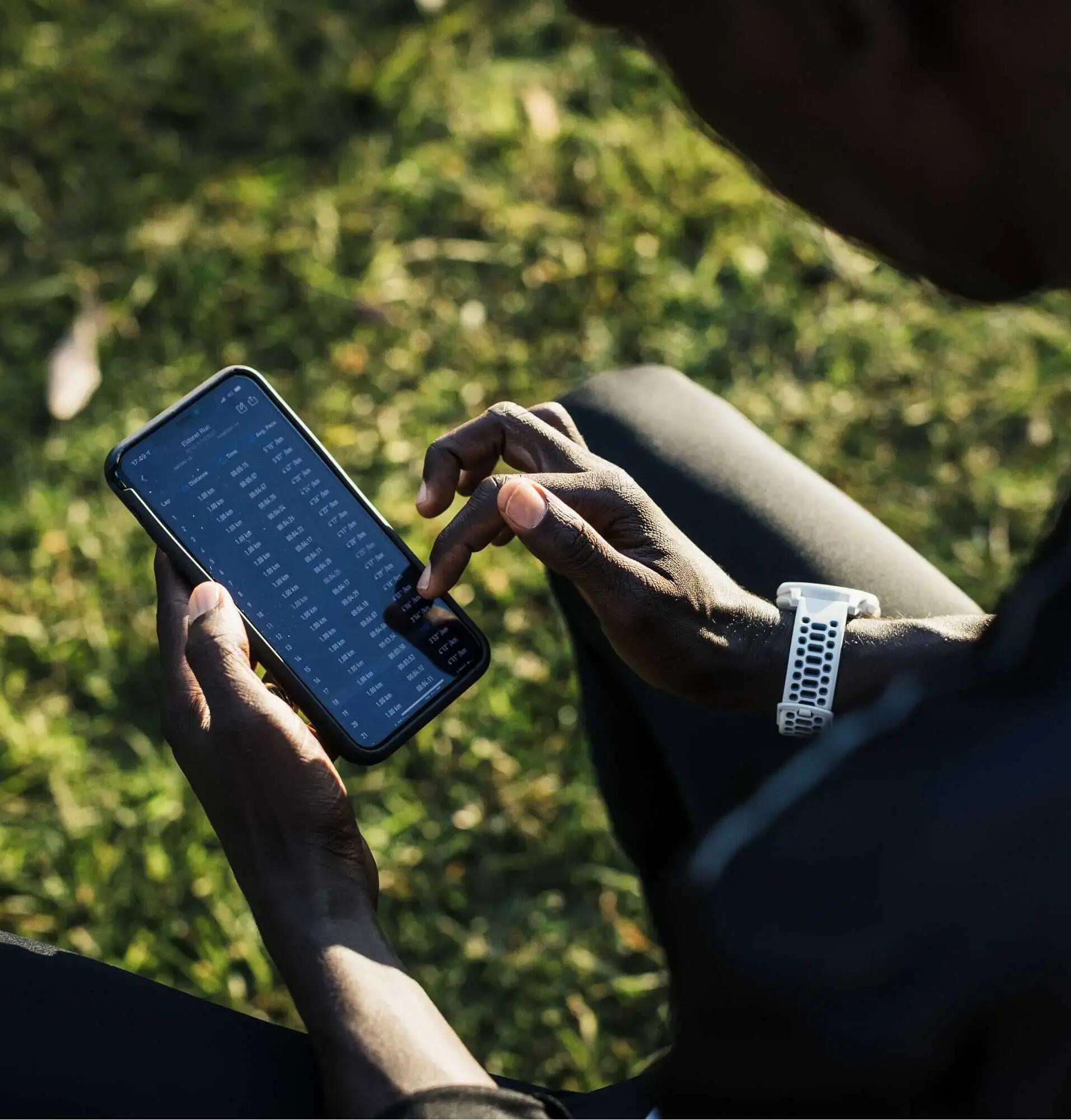 person holding smartphone and wearing a GPS watch