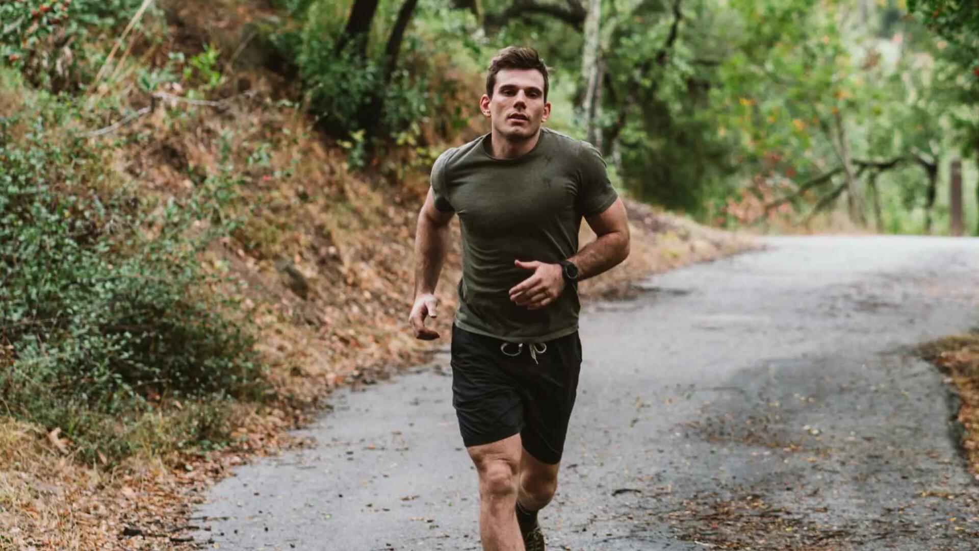 mężczyzna biegnący lasem w odzieży do biegania ze smartwatchem na ręce