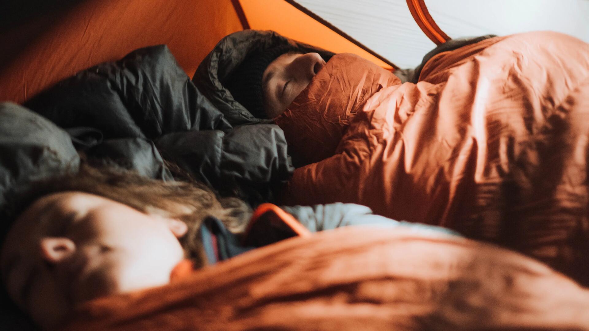 A man and woman tucked in, sleeping in their sleeping bags