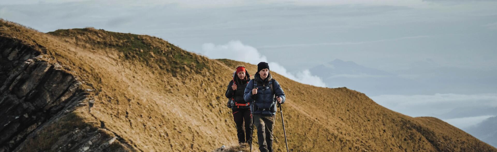 kobieta i mężczyzna wędrujący po górach w odzieży trekkingowej z kijami trekkingowymi w rękach